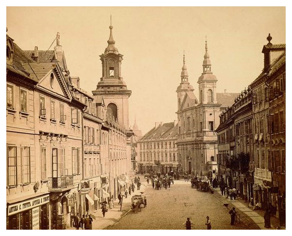 Ulica Freta w Warszawie. Fot. Maurycy Pusch, ok. 1895. Ze zbiorów Muzeum Narodowego w Warszawie
Warszawa. Ulica Freta. Widok w kierunku ulicy Nowomiejskiej, w głębi po prawej fasada kościoła pw. św. Ducha, po lewej wieża kościoła pw. św. Jacka. Pierwszy budynek od lewej, dwupiętrowy, z dwiema lukarnami i trójkątnym tympanonem z okrągłym oknem to kamienica pod numerem 16. Na pierwszym piętrze – balkon z ozdobną balustradą, na parterze – szyld apteki S. Tuguta w języku rosyjskim i polskim. Na chodniku przed wejściem stoi trzech mężczyzn i kobieta z parasolką. Na chodnikach i ulicy wielu przechodniów, na jezdni – szereg zaprzęgów konnych. Zdjęcie wykonano w słoneczny dzień.
