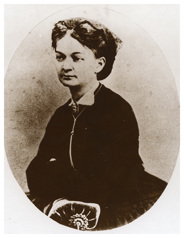 Bronisława z Boguskich Skłodowska, matka Marii. Ze zbiorów MMSC
Portret przedstawia Mariannę Bronisławę z Boguskich Skłodowską, matkę Marii. Zwrócona lekko lewym profilem w stronę obiektywu, patrzy przed siebie z łagodnym wyrazem twarzy. Ma ciemne włosy uczesane do tyłu z przedziałkiem na środku, na nich – koronkowy stroik w ciemnej tonacji. Ubrana w ciemny strój, spod którego wystaje biały kołnierzyk, spięty broszą. Na szyi – zawieszony długi wisiorek, którego koniec przesłaniają założone ramiona. Portretowana wspiera je na ozdobnej poduszce.