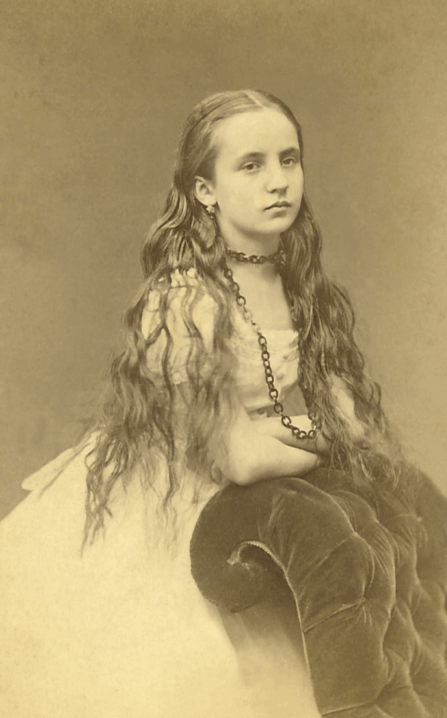 Helena Maria Rosen, fotografia z lat 1863–1874. Ze zbiorów Archiwum Akt Nowych
Fotografia portretowa w sepii przedstawia Helenę Marię Rosen w wieku dziewczęcym. Zwrócona lekko prawym profilem, spogląda z powagą. Stoi, opierając założone ręce na pikowanym oparciu fotela. Jej długie, uczesane z przedziałkiem na środku i sięgające za talię włosy, są lekko pofalowane. Portretowana ma na sobie jasną, szeroko rozkloszowaną suknię z krótkimi, bufiastymi rękawkami. Prawe ucho zdobi krótki wiszący kolczyk, szyję okala łańcuszek o grubych oczkach, który następnie opada na wsparte o fotel lewe przedramię.